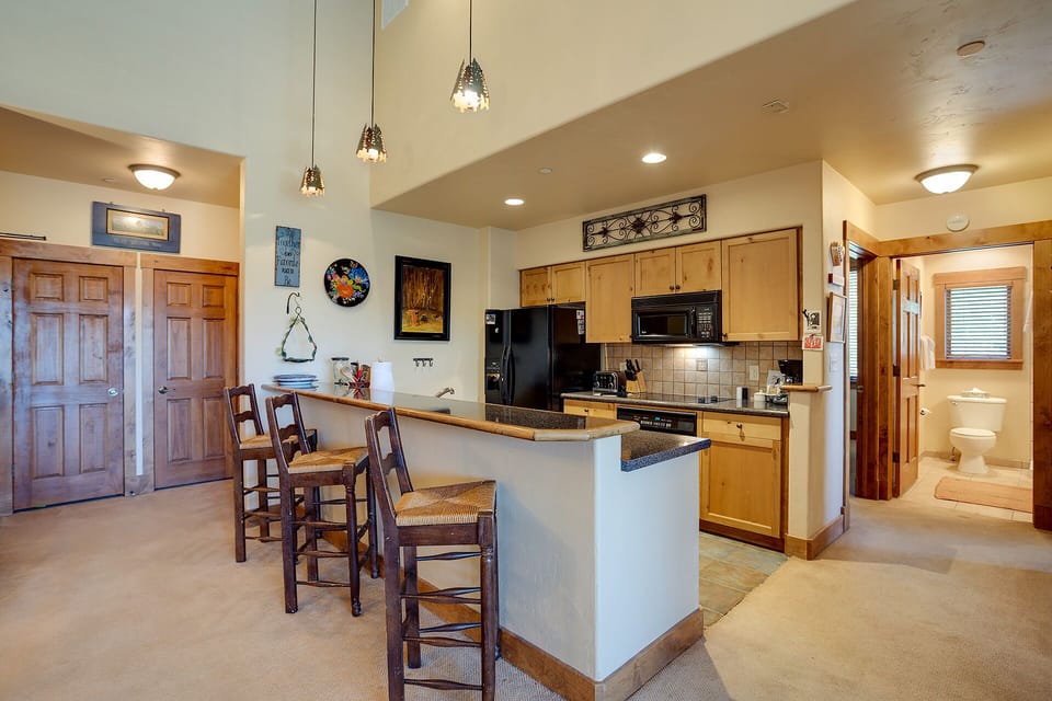 Your spacious open-concept kitchen welcomes you with warm wood cabinetry, granite counters, and a breakfast bar perfect for morning coffee.