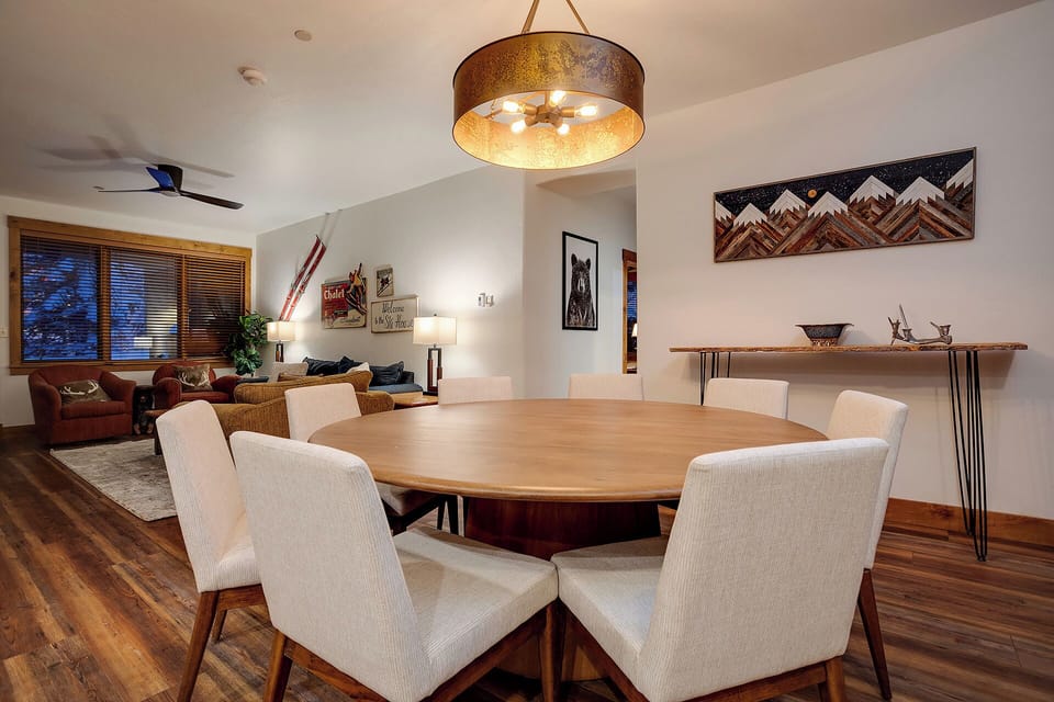 Gather around this stunning round dining table for memorable meals with your group, illuminated by warm pendant lighting in this thoughtfully designed space.