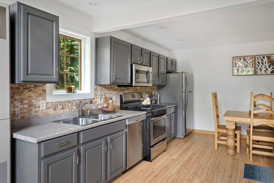 Fully equipped kitchen with stylish gray cabinets and stainless steel appliances.