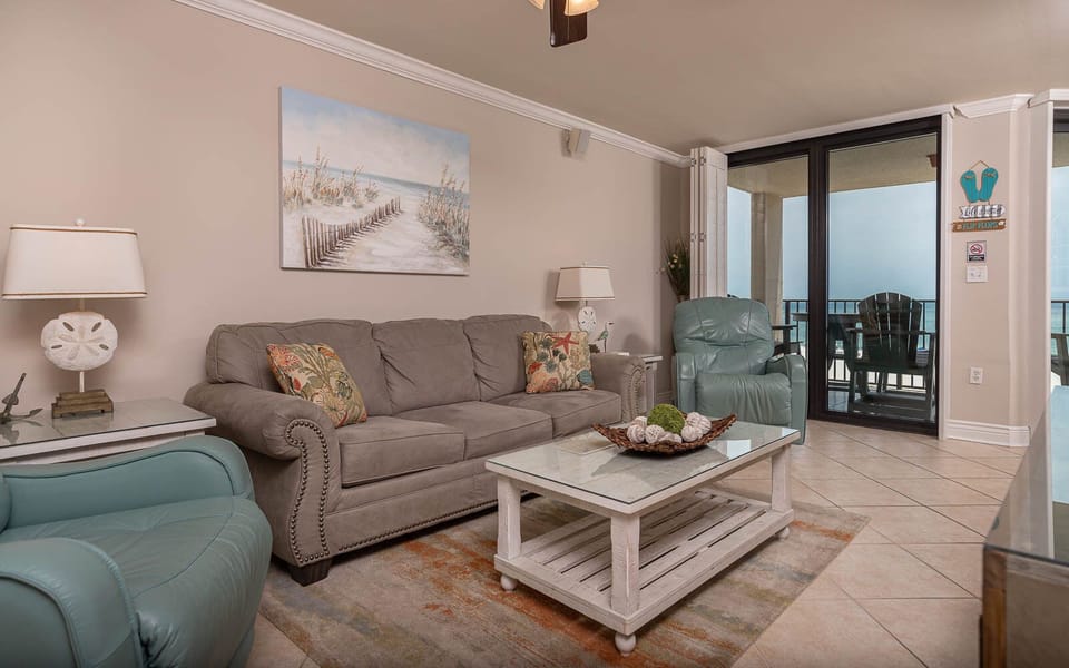 Relax in the spacious living area, featuring a comfortable sofa with queen sleeper, vibrant decor, and a beachfront view