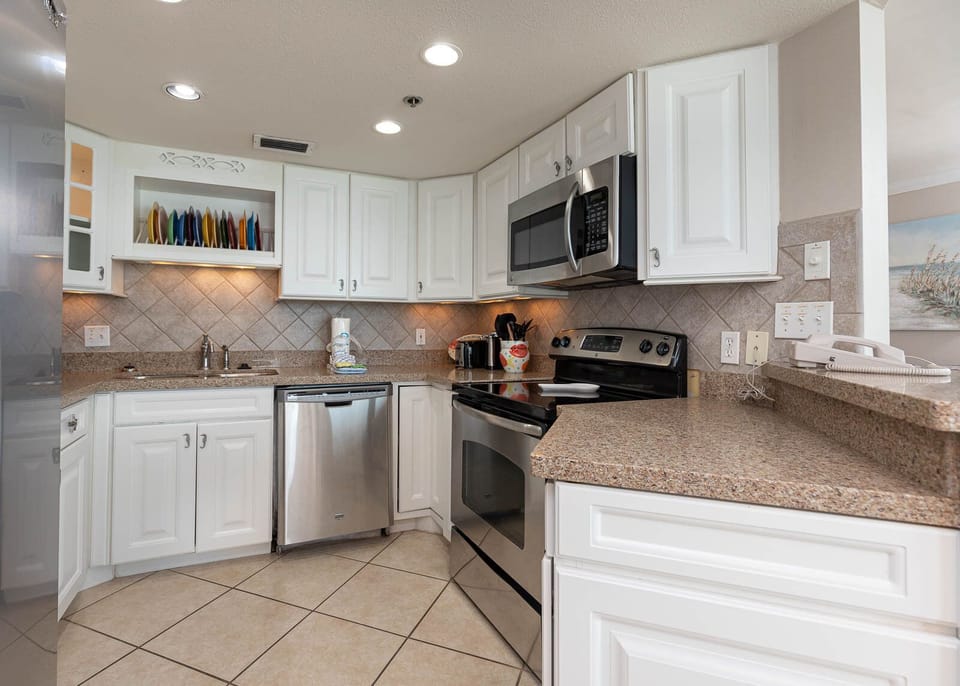 Cook comfortably in this kitchen featuring stainless appliances, ample counter space, and colorful dishware on display