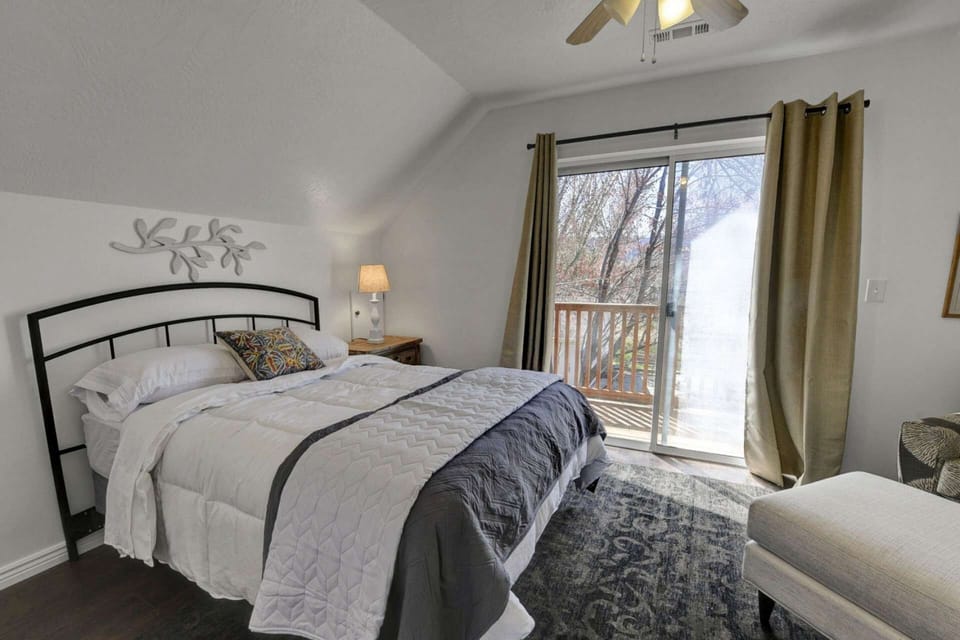 South Side Bedroom with Full Size Bed, Private Balcony overlooking the Backyard, Sitting Chair and Ottoman for Suitcase, Closet and Bedside Table.