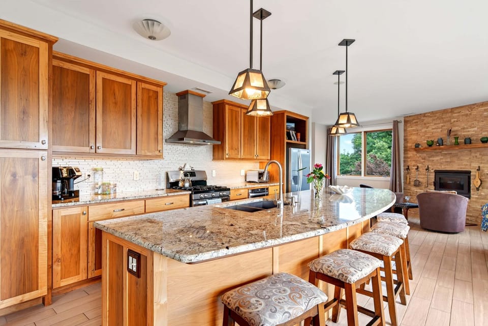 Main-level chef's kitchen with gas range, dishwasher, standard + Keurig coffee makers, and a kitchen island with seating for 6.