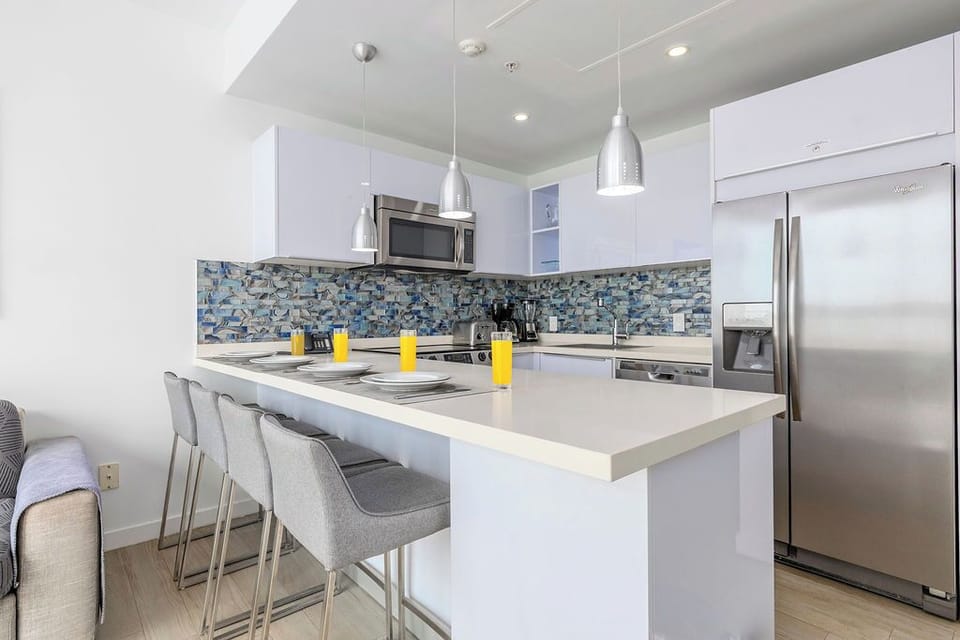 Gather at this bright kitchen island for morning coffee or casual meals. The sleek space features modern appliances and a stylish backsplash, ready for your culinary adventures.