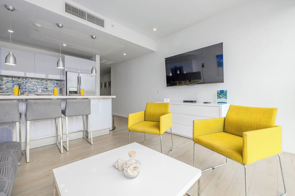 You'll love the cheerful pops of yellow in this bright, modern living space where you can unwind on comfy seating, cook in the open kitchen, and enjoy entertainment on the flat-screen TV.