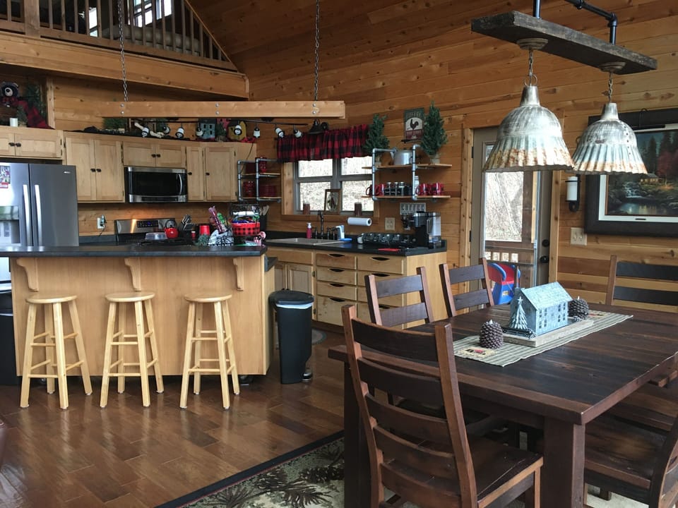 Dining with large barnwood table and baby high chair. Kitchen with bar