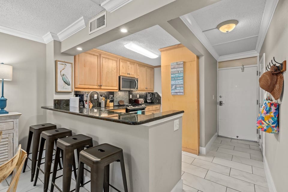 This fully furnished kitchen is equipped for easy vacation meals, featuring full-size appliances, generous counter space, and bar seating for four. Open to the main living area, it offers both convenience and a welcoming space to gather.