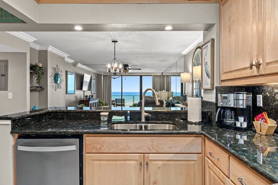 That view really is the star. From the kitchen, you can see straight through the condo, past the balcony, and out to the emerald Gulf—making even morning coffee and quick meals feel like part of the vacation.