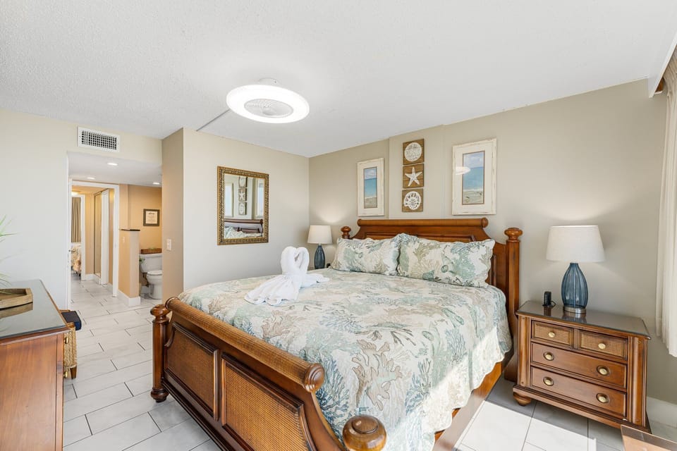 The primary suite offers a peaceful, coastal-inspired retreat with a king bed, soothing décor, and private access to the ensuite bath—creating a comfortable, inviting space to relax, recharge, and wake up refreshed for another day at the beach.