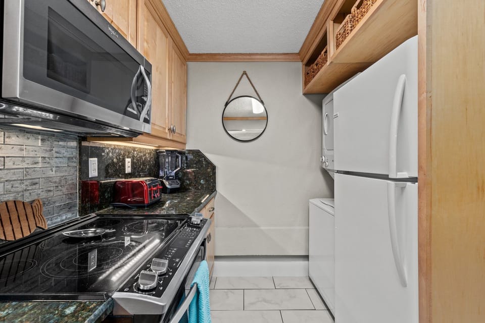 The galley kitchen is equipped with residential-style appliances, including a stove, dishwasher, refrigerator, and in-unit washer and dryer for added convenience during your stay.
