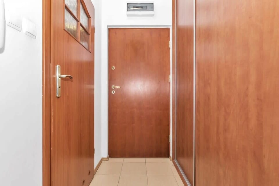 A hallway with wooden doors and built-in closets provides a practical entry space. The sleek design and neutral tones make it a functional yet attractive area.
