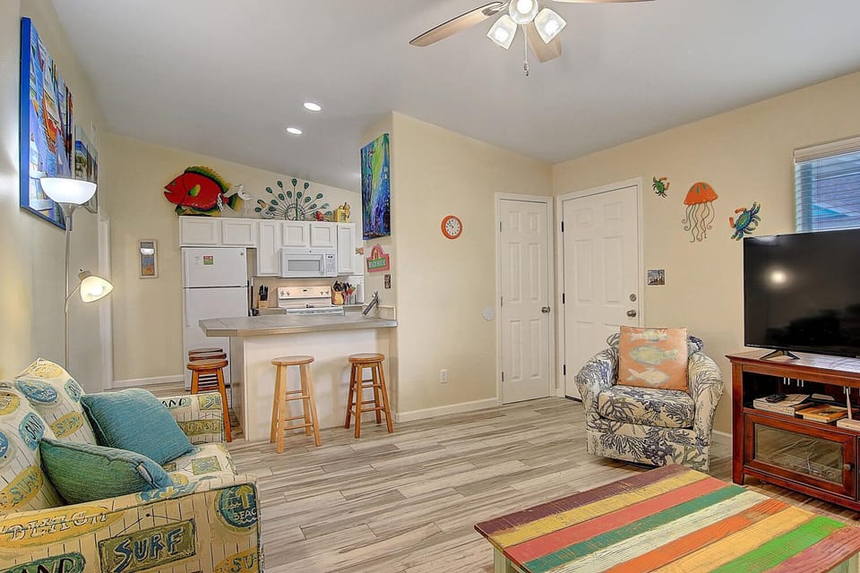 Relax in your cheerful living space with vibrant ocean-themed decor, open kitchen, and cozy seating perfect for beach vacation vibes.
