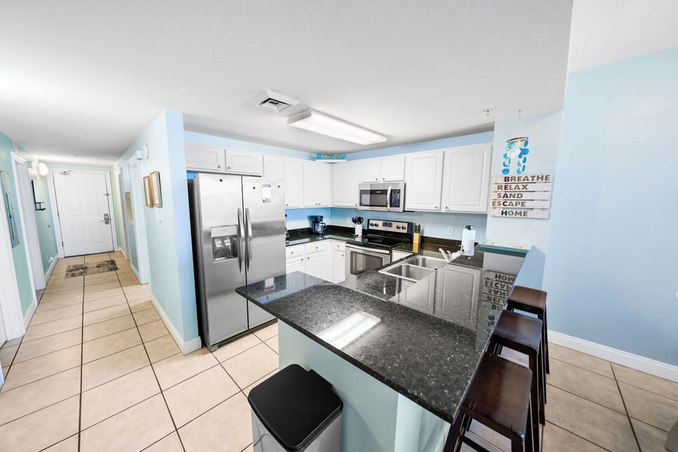 Your fully equipped kitchen awaits with granite counters, stainless appliances, and coastal charm for creating memorable meals together.