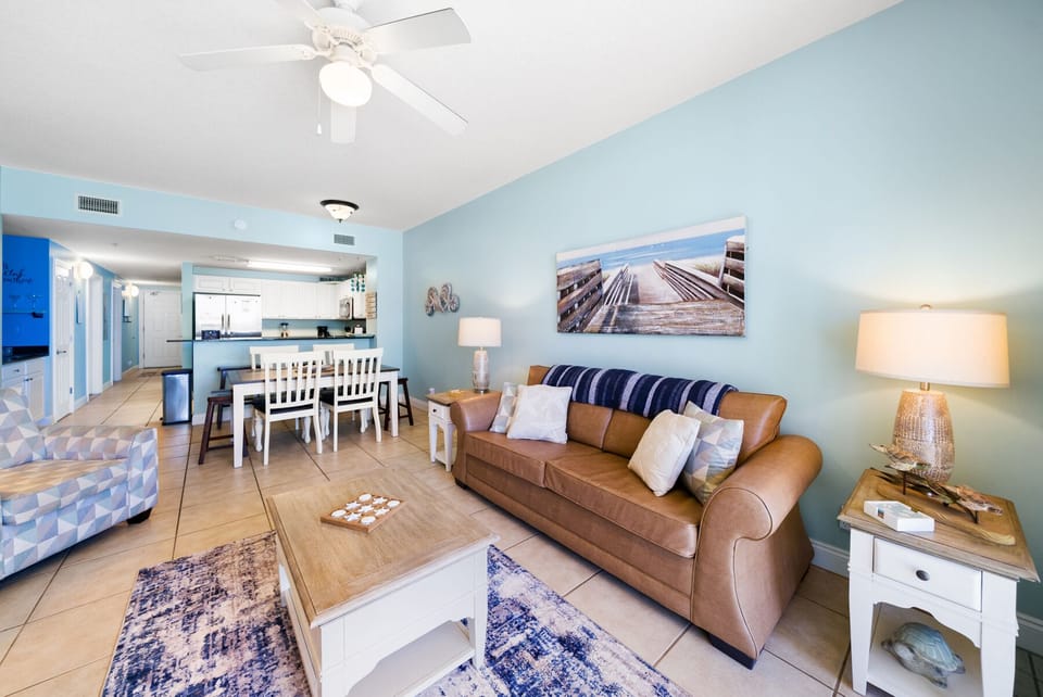 Relax in your bright, open living space with leather sofa, coastal decor, and fully equipped kitchen perfect for memorable beach getaways.