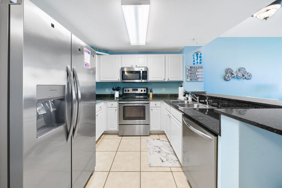 Your fully equipped kitchen features modern stainless steel appliances, granite countertops, and peaceful blue walls perfect for home cooking.