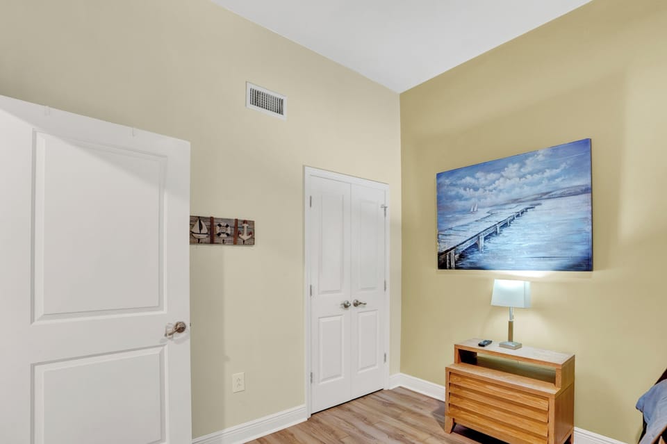 Your peaceful bedroom corner features warm coastal artwork and modern furnishings, creating a serene retreat after busy days exploring.