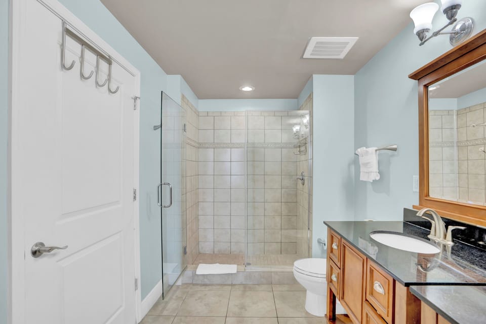 Refresh in your spacious bathroom featuring a walk-in shower, elegant granite countertops, and soothing blue walls that create a spa-like retreat.