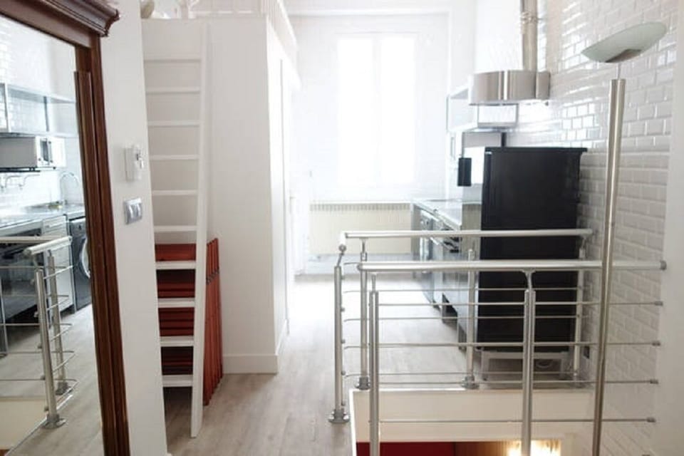 Ladder towards the small loft and stairs descending into the bedroom