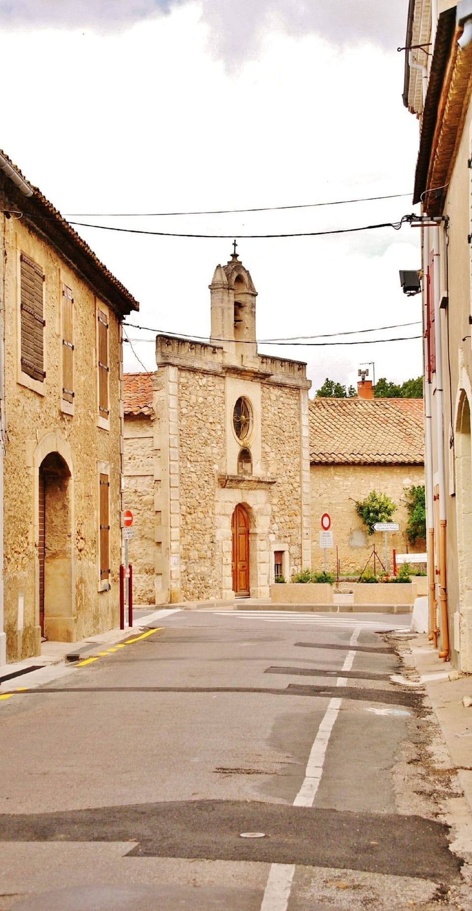 A quiet village street and stone church in Sallèles-d'Aude, France.