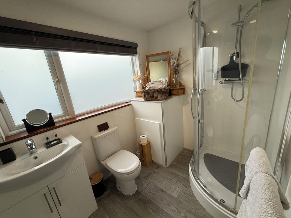 Bathroom with walk in shower and heated towel rail, sink and toilet, lots towels