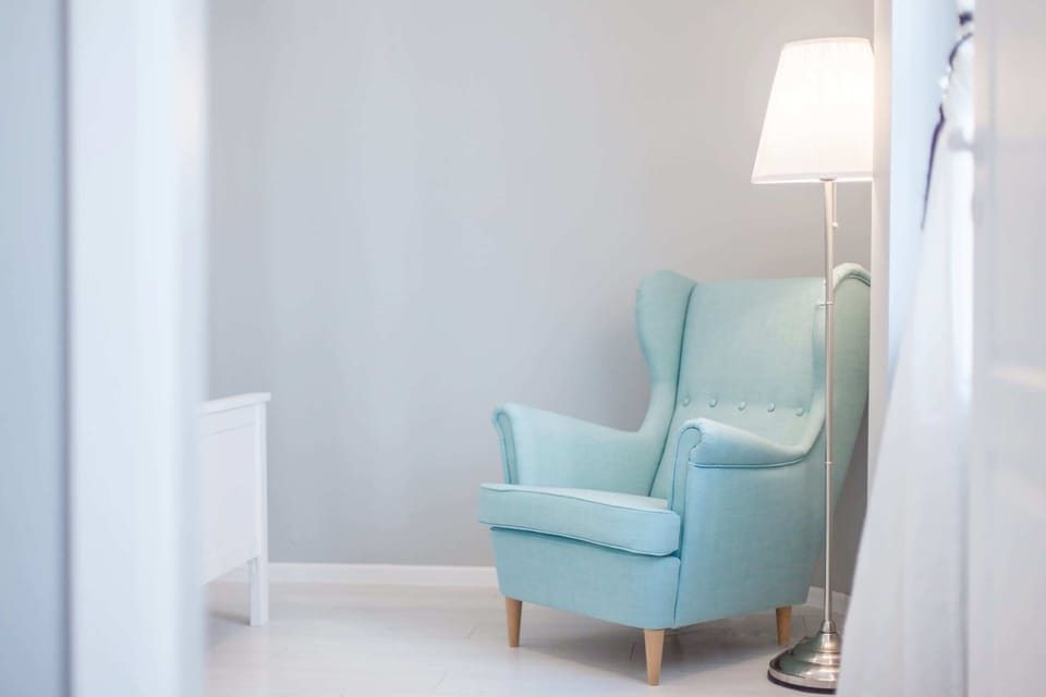 Armchair and lamp in the cozy bedroom with a double bed.
