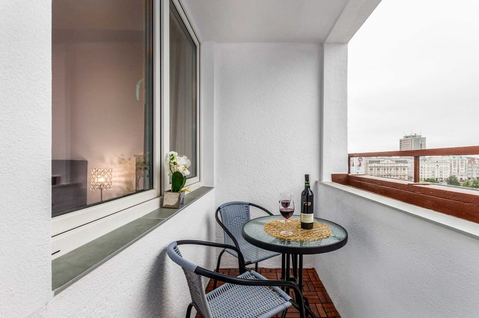 A cozy outdoor terrace featuring a small round table with two glasses of wine, offering a panoramic view of the city, making it an ideal space for relaxing.