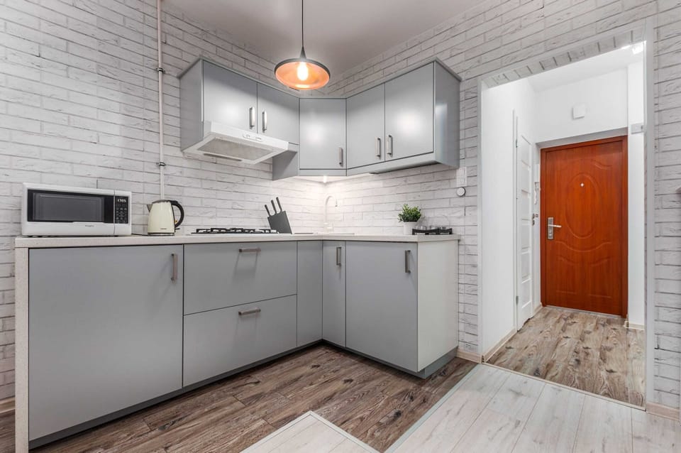 Functional and practical kitchenette with gray cabinets, a microwave and an electric kettle on the counter.