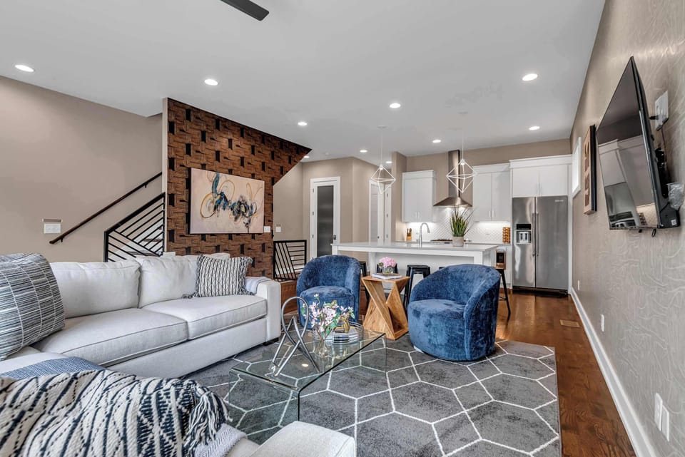 Located on the 2nd floor, the bright and spacious open-concept living room features a comfortable sectional sofa, cozy accent chairs, a Smart TV, and large windows that fill the space with natural light
