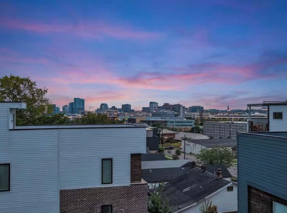 Spacious private rooftop deck with comfortable lounge seating, string lights, and beautiful skyline and sunset views.
