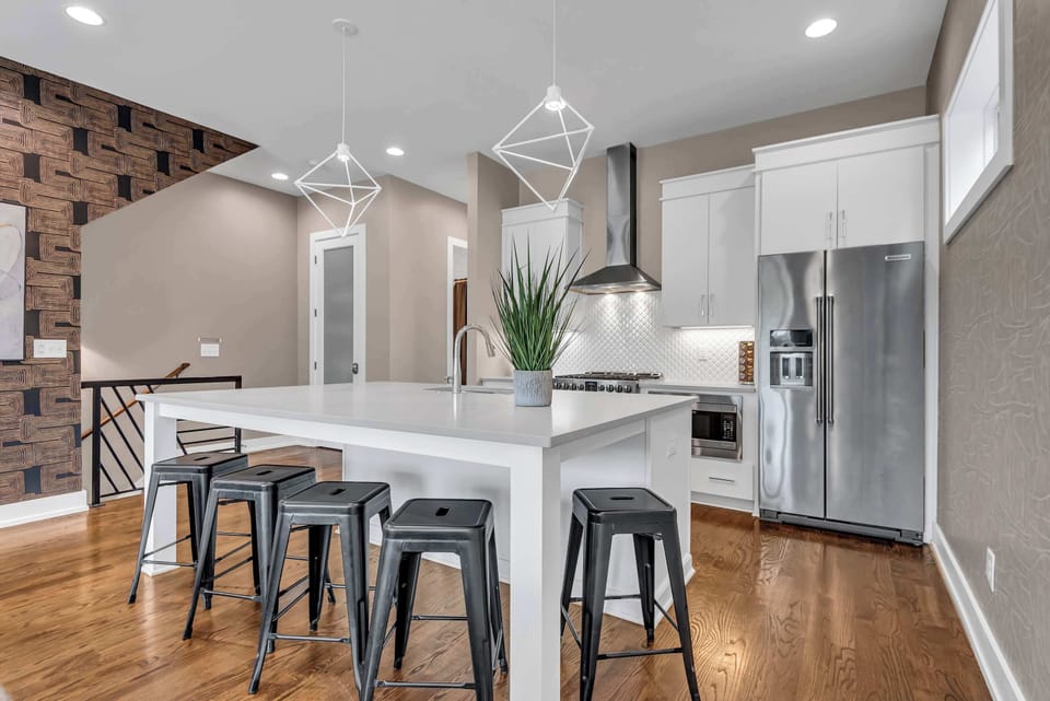 Located on the 2nd floor, the modern, fully-equipped kitchen features a spacious island with bar seating, stainless steel appliances, ample cabinetry, and an open layout connecting seamlessly to the living area.
