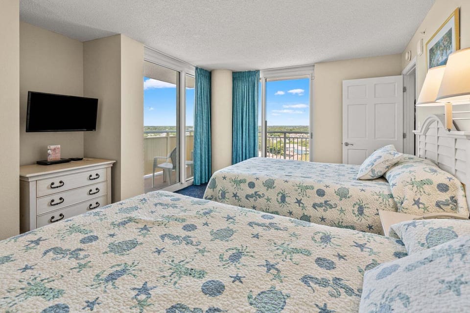 Bedroom with two beds, a wall TV and sliding doors to the balcony at Avista Ocean Resort 1514, Ocean Drive