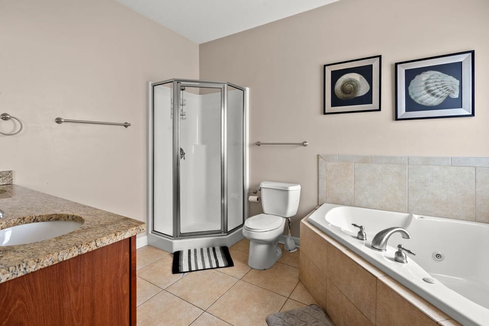 Bathroom with a walk-in shower, tub and long counter at Palmetto Coast, Villa B, a 5-bedroom Crescent Beach rental