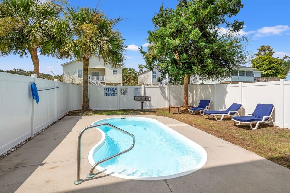 Poolside lounge chairs, palms and a grill at Palmetto Coast, Villa B, a 5-bedroom Crescent Beach vacation rental