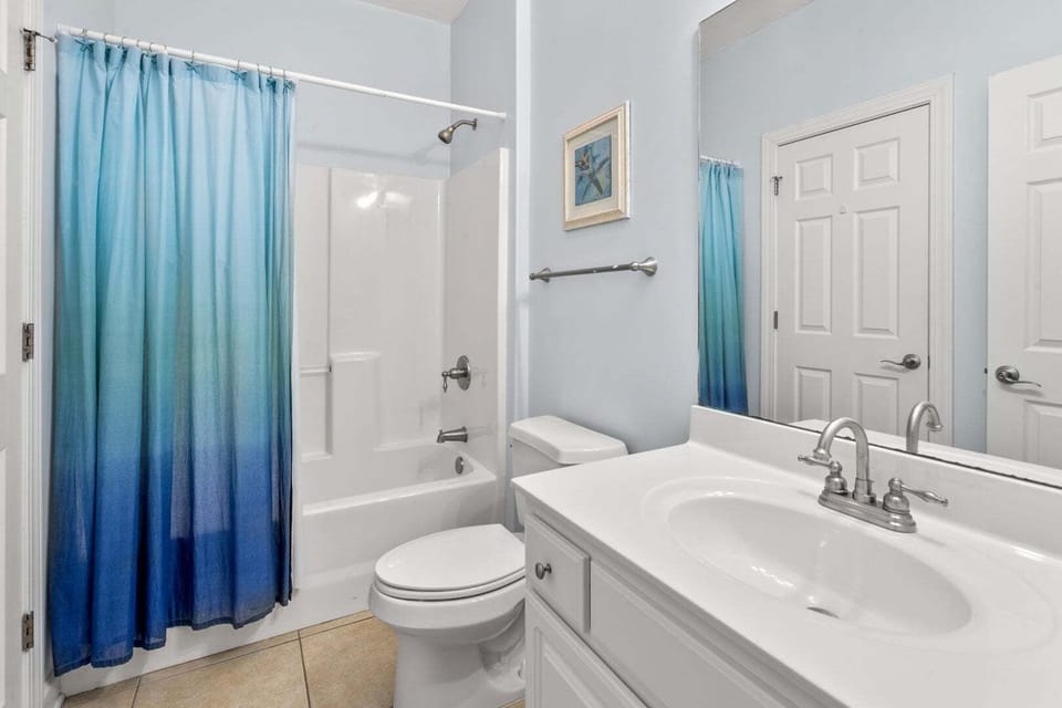 Blue shower curtain and a white vanity in a bright bathroom at Palmetto Coast, Villa B in Crescent Beach