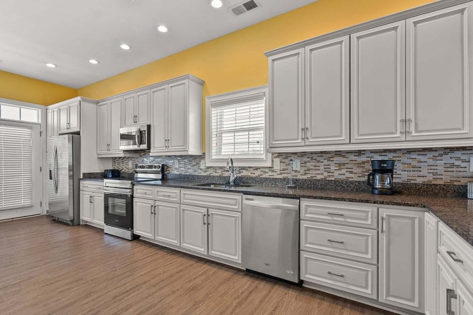 Bright kitchen with white cabinetry and a yellow accent wall at Another Day in Paradise in Cherry Grove