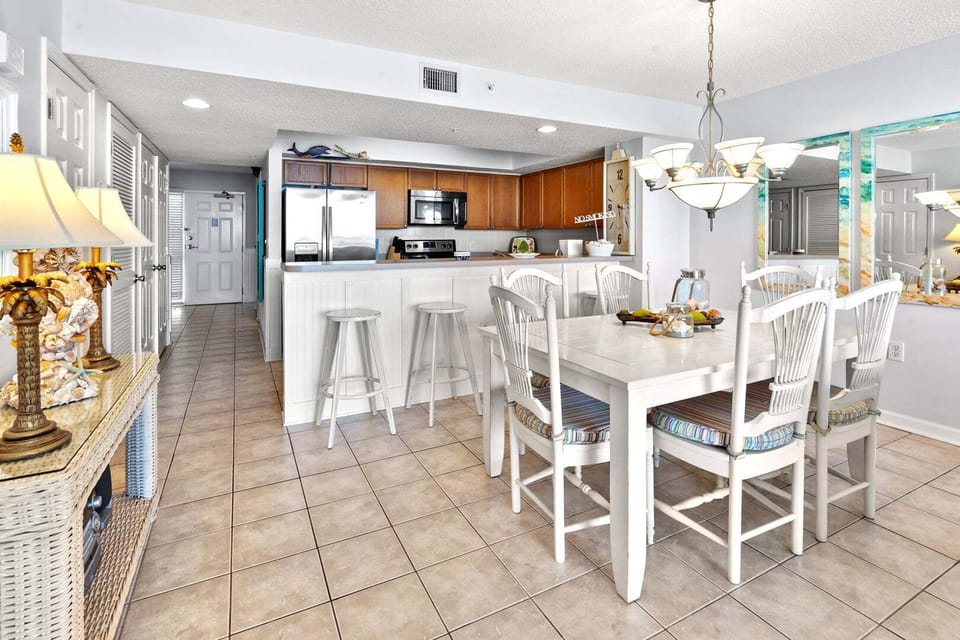 Dining table, bar stools and white cabinetry in the kitchen at Ocean Bay Club 703, an Ocean Drive vacation rental