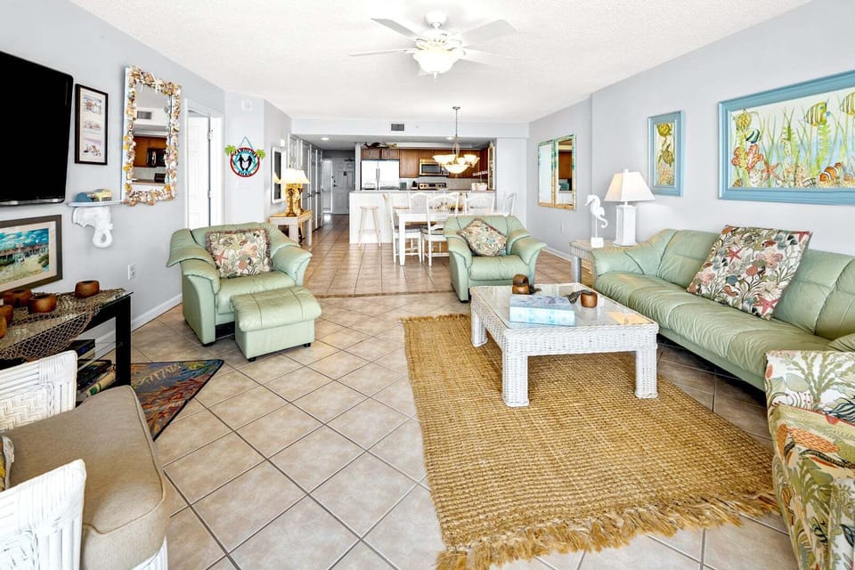 Light green sofas and a ceiling fan fill the open living space at Ocean Bay Club 703 in Ocean Drive, North Myrtle Beach