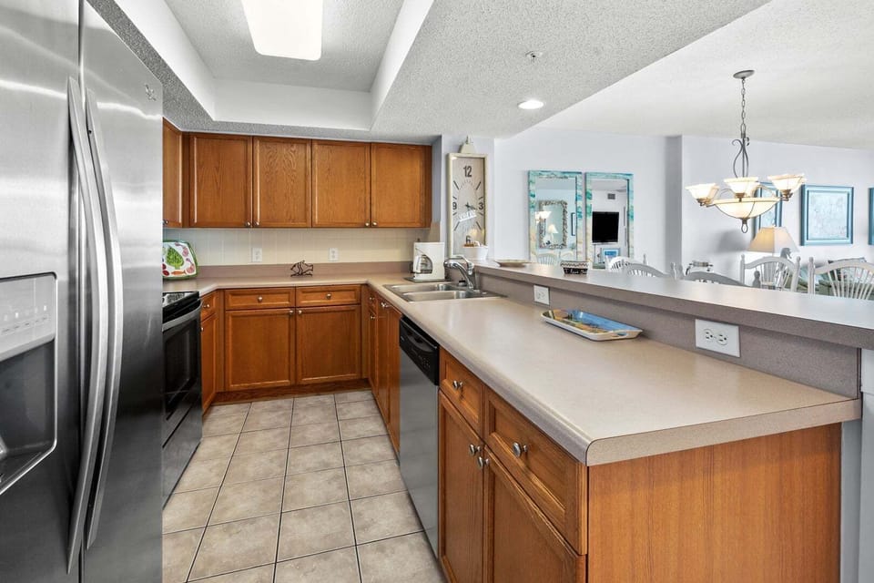 Kitchen island with a two-basin sink and brown cabinetry at Ocean Bay Club 703, a 3-bedroom Ocean Drive condo