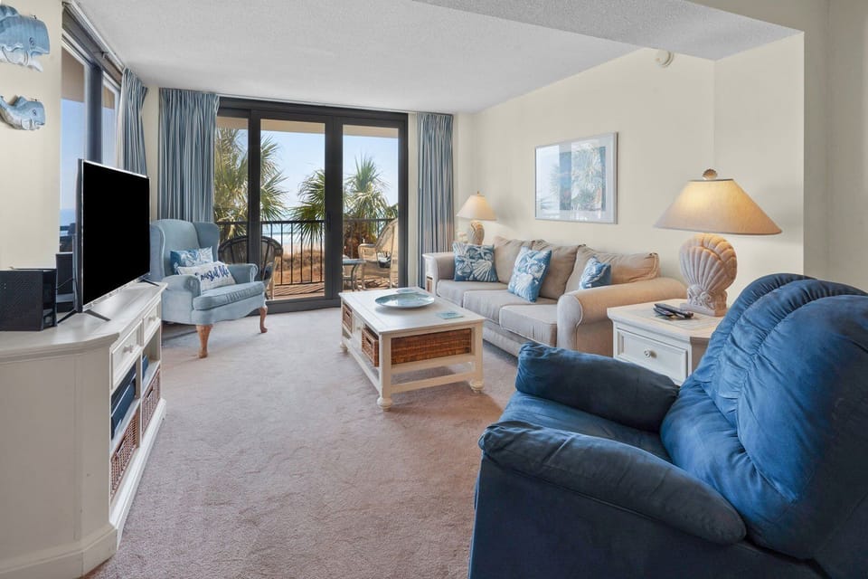 Blue armchair and sectional facing the ocean-view sliders at Crescent Sands of Crescent Beach L2