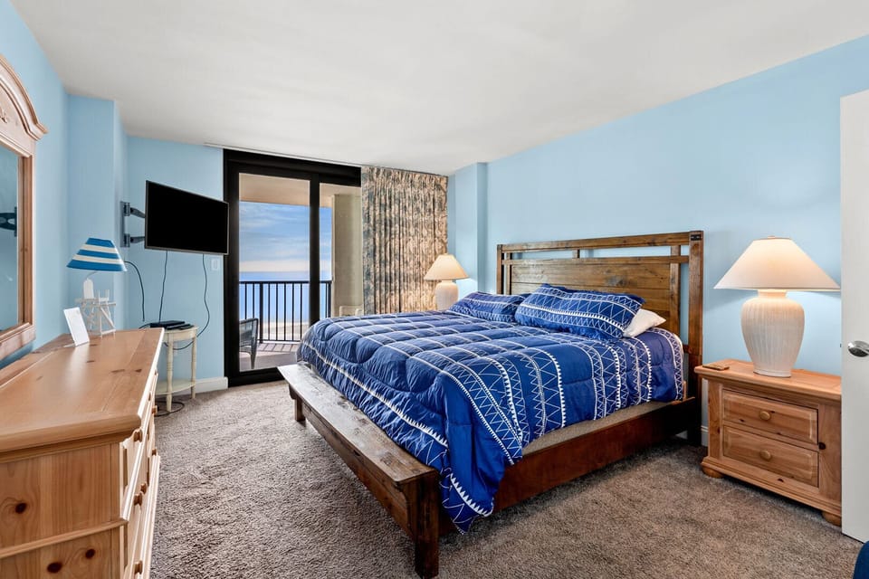 Bedroom with blue bedding and a sliding door to the balcony at Crescent Sands of Crescent Beach I6