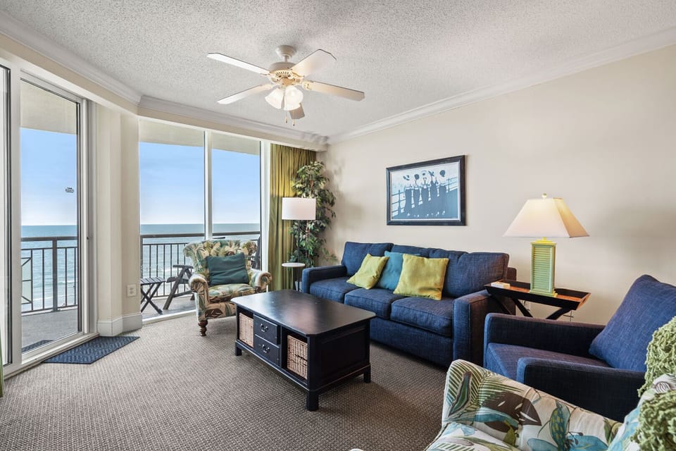 Coastal artwork and balcony doors beside the blue sectional at Mar Vista Grande 712 on Ocean Drive