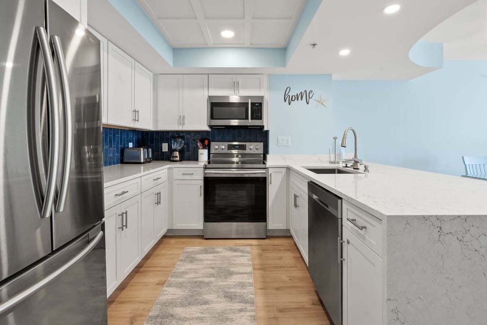 Full kitchen with white cabinetry and a blue backsplash at Beachwalk Villas 406, a Cherry Grove condo rental