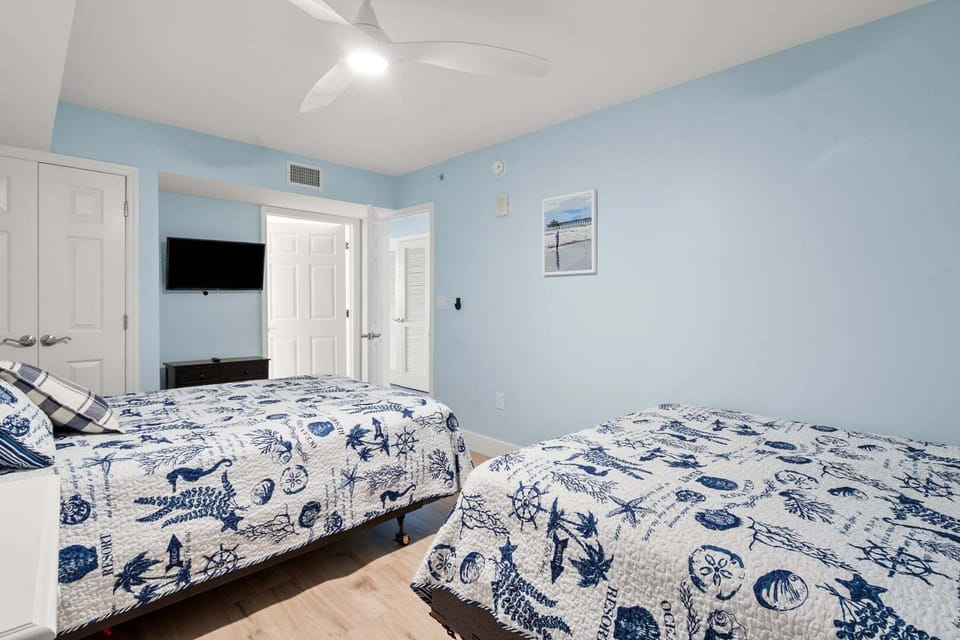 Nautical bedroom with two beds and a wall-mounted TV at Beachwalk Villas 406 in Cherry Grove