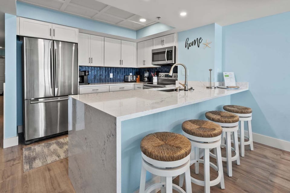 Kitchen island with bar stools and white cabinetry at Beachwalk Villas 406 in Cherry Grove, North Myrtle Beach