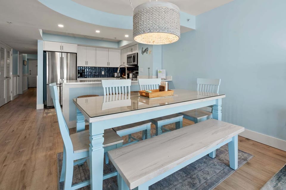 Glass-topped dining table with bench seating beside the kitchen island at Beachwalk Villas 406, Cherry Grove