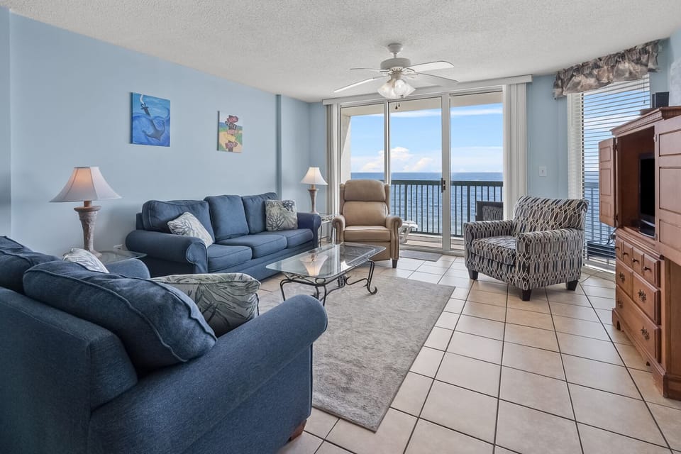 Blue sofas and balcony doors in the living area of Ashworth 702, a 3-bedroom Ocean Drive vacation rental