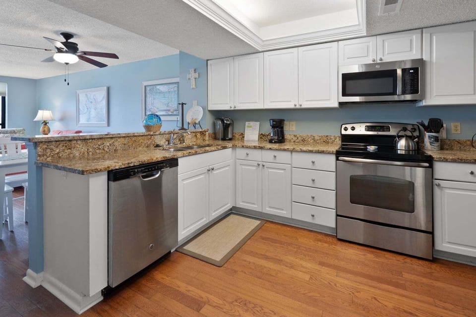 Kitchen with white cabinetry, full-size appliances and a breakfast counter at Windemere 703, Ocean Drive