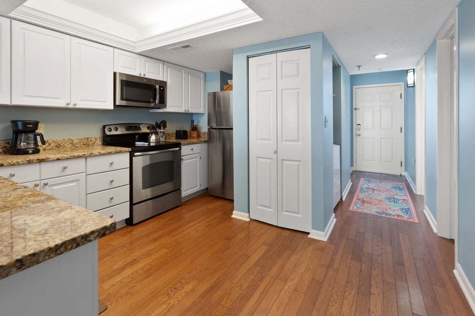 White cabinetry and dark counters line the kitchen at Windemere 703, a 3-bedroom North Myrtle Beach condo