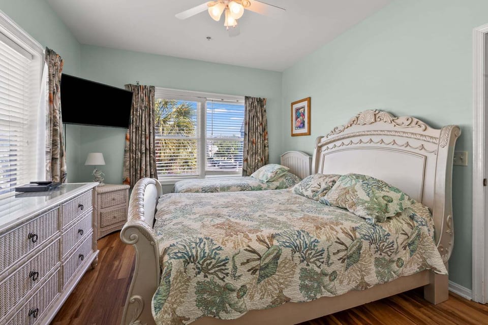 Two beds with patterned bedding under a ceiling fan at Diamond Dunes B in Crescent Beach, North Myrtle Beach