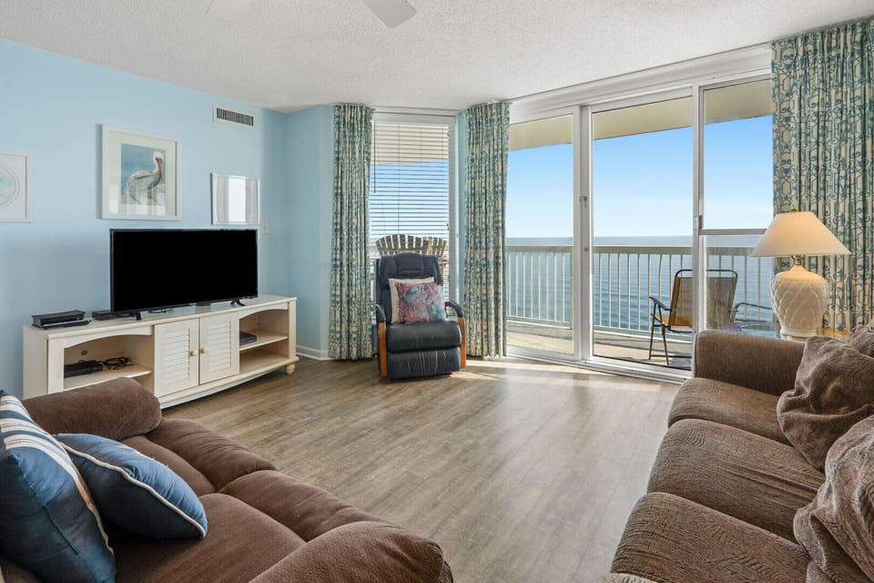 Sectional sofa and recliner face the ocean-view balcony doors at Paradise Pointe 11A, a 4-bedroom Cherry Grove condo